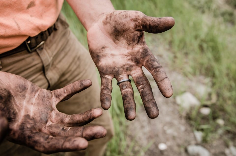 A man with his hands covered with mud